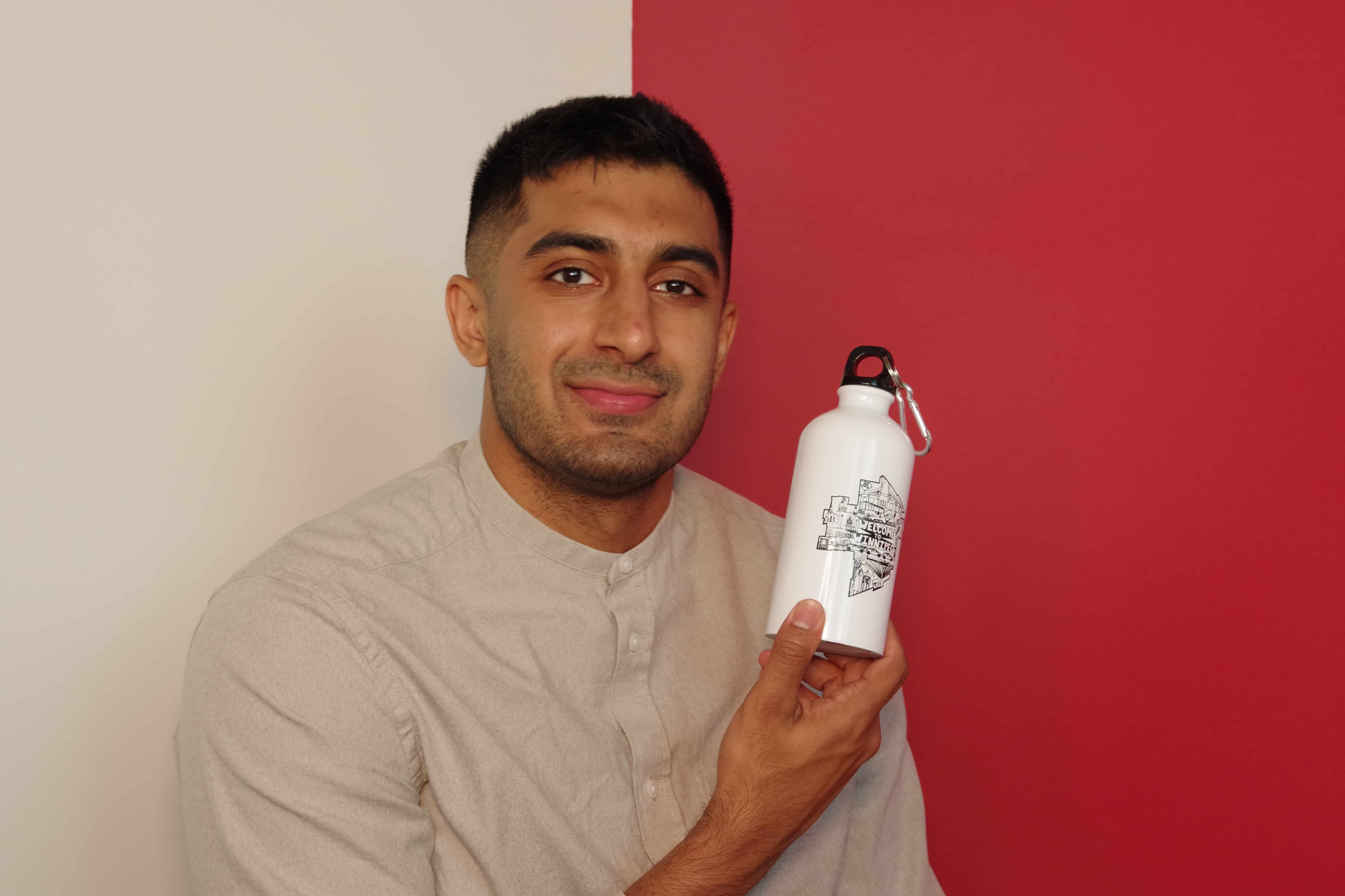Main Street Project marketing coordinator, Raj Sidhu holding a water bottle donated to their shelter program.