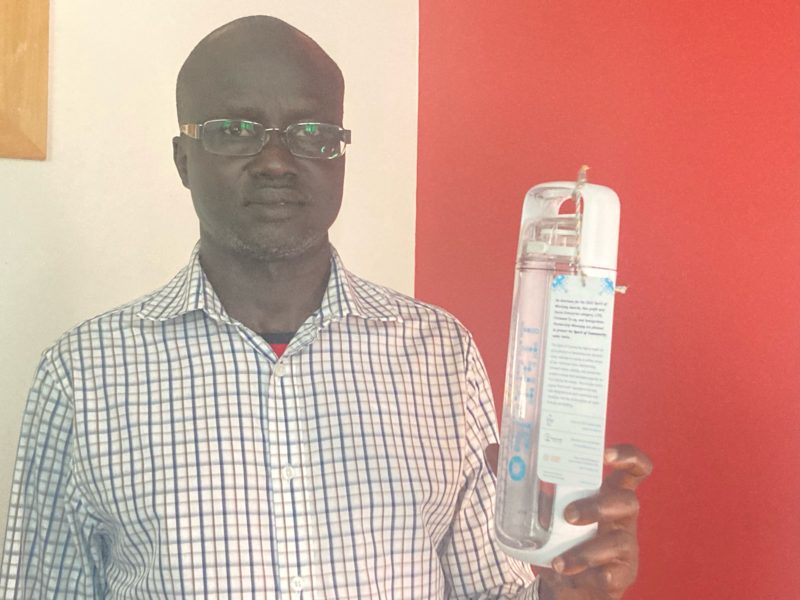 Reuben Garang of Immigration Partnership Winnipeg, holding a Spirit of Community water bottle